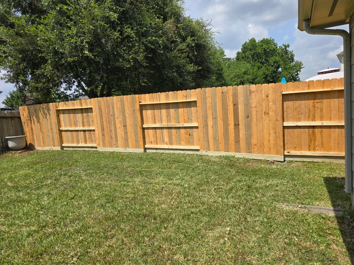 Tall wood fence and fresh lawn along a property line